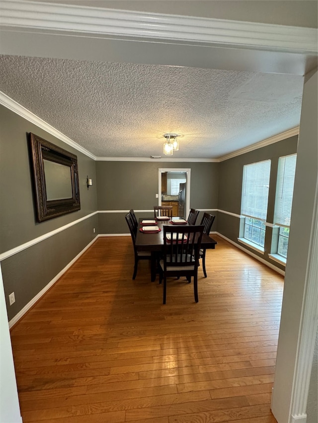 dining space with a textured ceiling, hardwood / wood-style floors, and ornamental molding