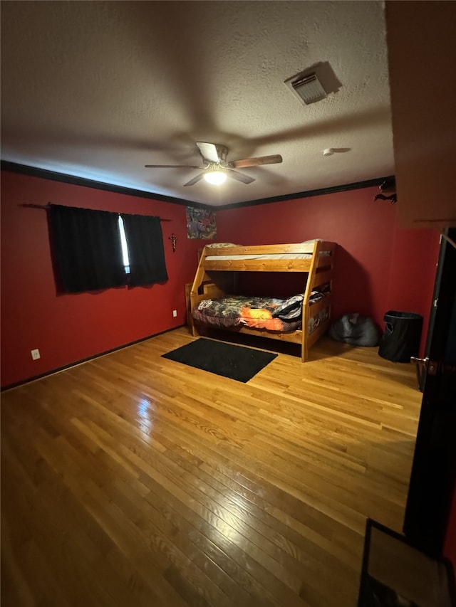 bedroom with hardwood / wood-style flooring, a textured ceiling, and ceiling fan