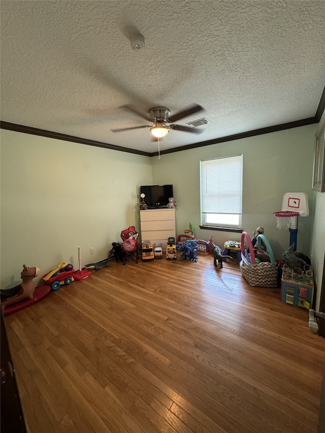 interior space with a textured ceiling, ceiling fan, crown molding, and wood-type flooring