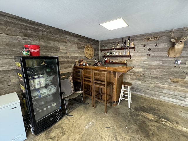 bar featuring wooden walls, concrete floors, and white fridge