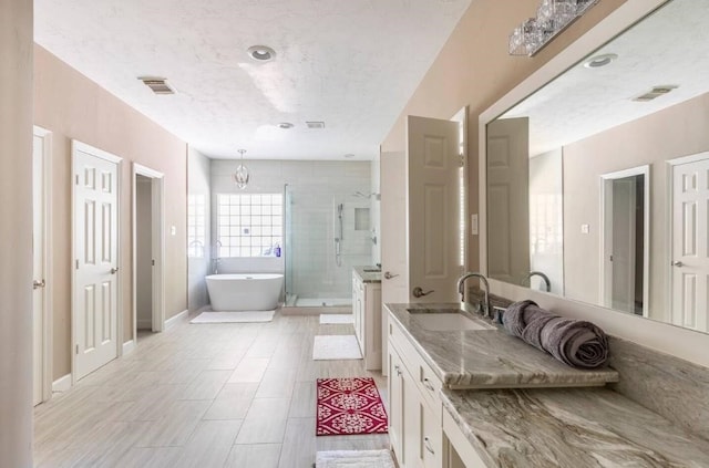 bathroom with a stall shower, baseboards, visible vents, a soaking tub, and vanity