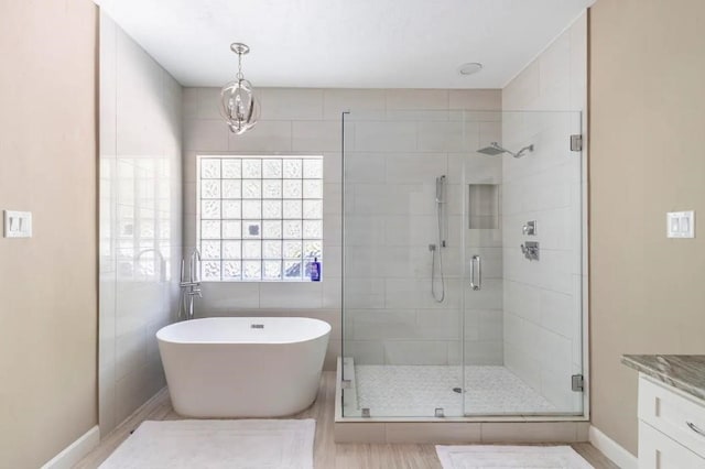 full bathroom featuring a stall shower, vanity, baseboards, and a soaking tub