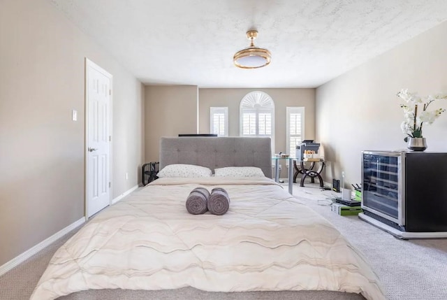 carpeted bedroom featuring beverage cooler and baseboards