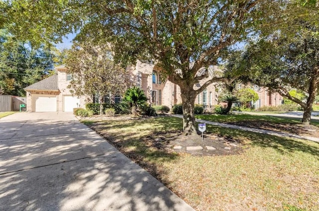 view of property hidden behind natural elements with driveway, an attached garage, fence, and a front yard