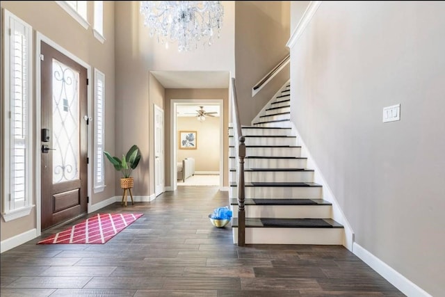 foyer featuring wood finished floors, a towering ceiling, baseboards, stairway, and radiator heating unit