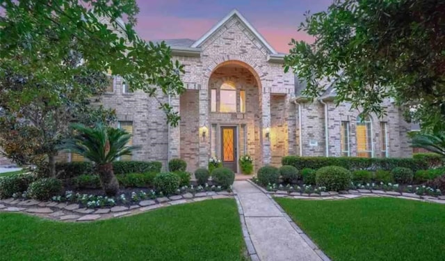 view of front of home with a yard and brick siding