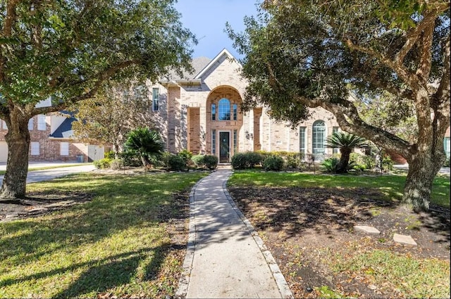 view of front facade with brick siding and a front yard