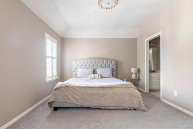 carpeted bedroom featuring vaulted ceiling, baseboards, and ensuite bathroom