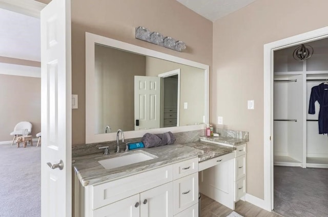 full bathroom featuring a walk in closet, vanity, and baseboards