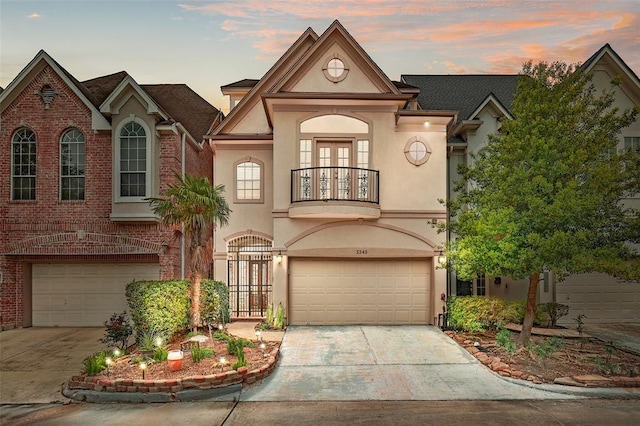 view of front of home with a balcony, an attached garage, concrete driveway, and stucco siding