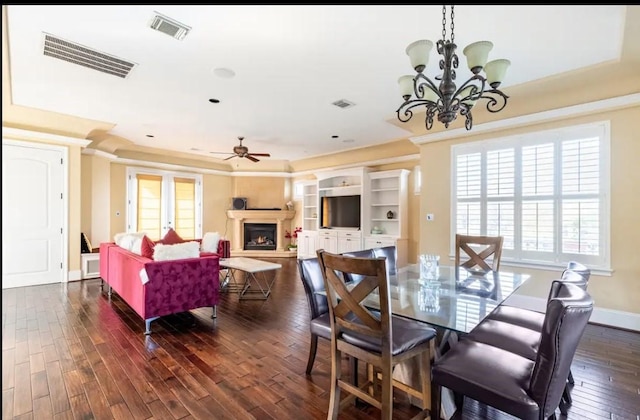 dining space featuring ceiling fan with notable chandelier and dark wood-type flooring