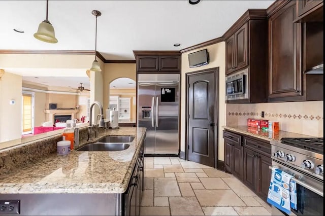 kitchen with dark brown cabinetry, sink, hanging light fixtures, built in appliances, and decorative backsplash