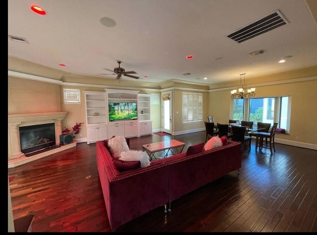 living room featuring dark hardwood / wood-style floors, a premium fireplace, and ceiling fan with notable chandelier