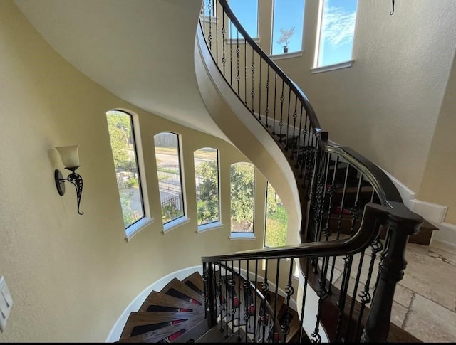 staircase featuring a towering ceiling and a wealth of natural light