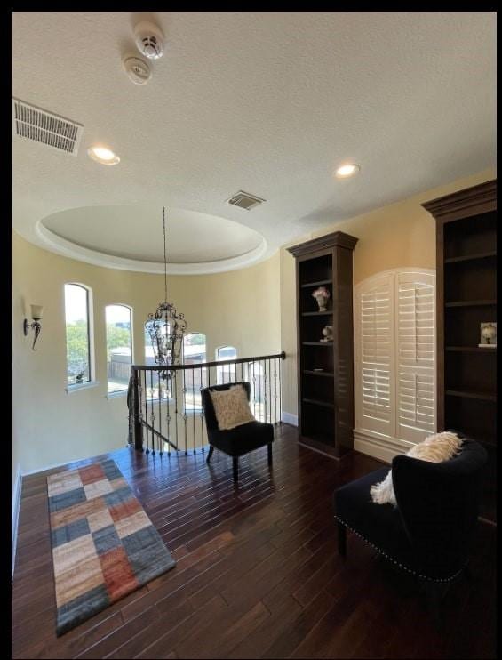 sitting room with dark hardwood / wood-style floors, a textured ceiling, and a tray ceiling