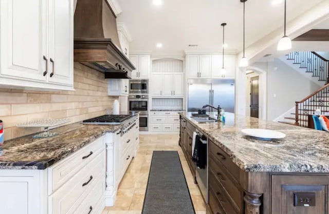 kitchen with tasteful backsplash, custom exhaust hood, built in appliances, a large island, and white cabinets