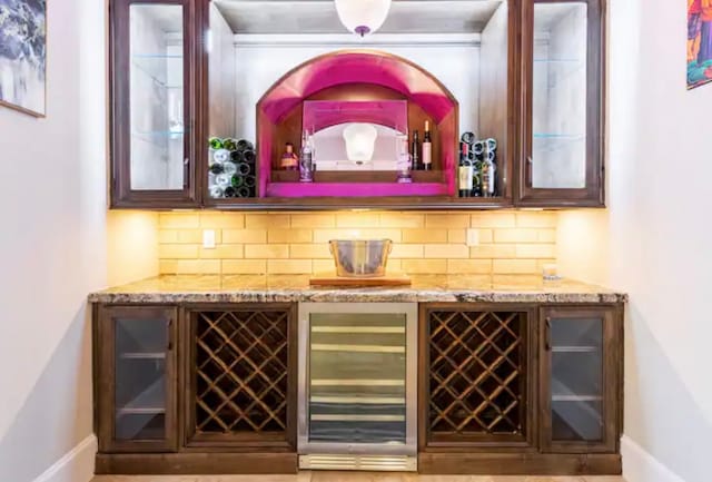 bar featuring backsplash, light stone counters, and beverage cooler