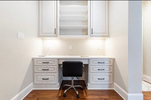 home office with built in desk and hardwood / wood-style floors