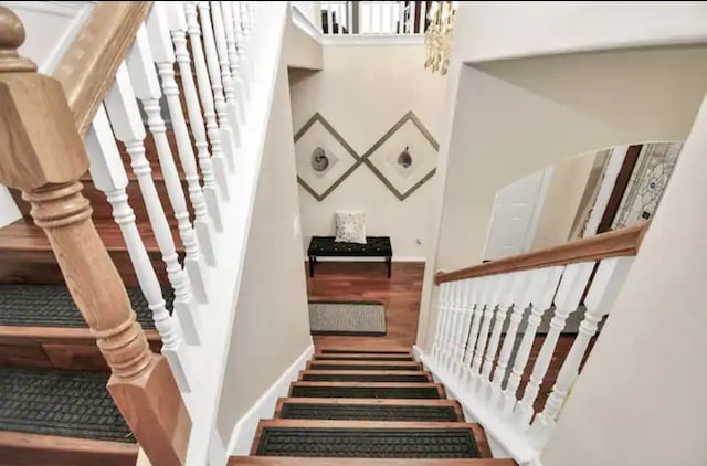 staircase featuring wood-type flooring and a towering ceiling