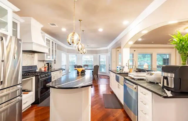 kitchen featuring a kitchen island with sink, custom exhaust hood, dark hardwood / wood-style floors, and stainless steel appliances