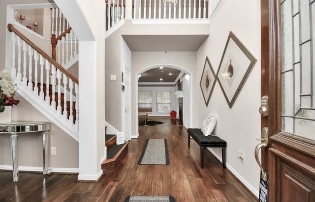 entryway featuring a high ceiling, crown molding, and dark wood-type flooring