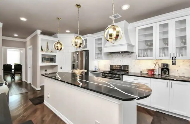 kitchen featuring appliances with stainless steel finishes, hanging light fixtures, a kitchen island, and custom exhaust hood