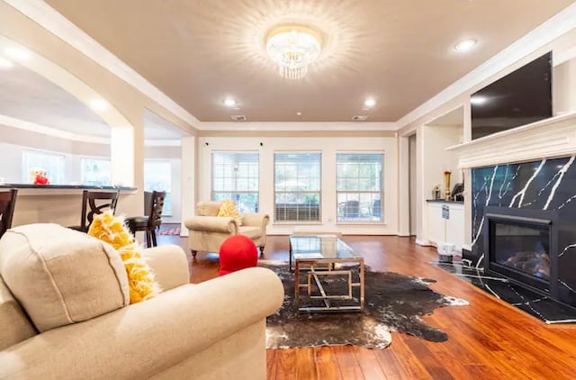 living room featuring a premium fireplace, hardwood / wood-style floors, ornamental molding, and a wealth of natural light