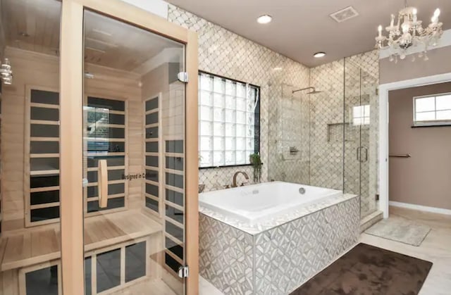 bathroom with a notable chandelier, tile flooring, tile walls, and plus walk in shower