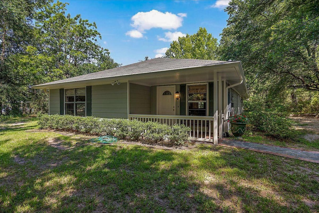 view of front of property with a front lawn, covered porch, and roof with shingles