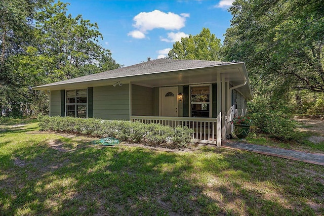 view of front of property with a front lawn, covered porch, and roof with shingles