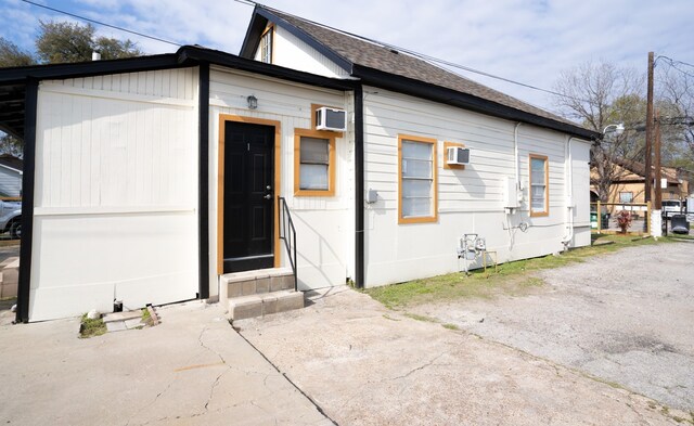 exterior space with a wall mounted air conditioner