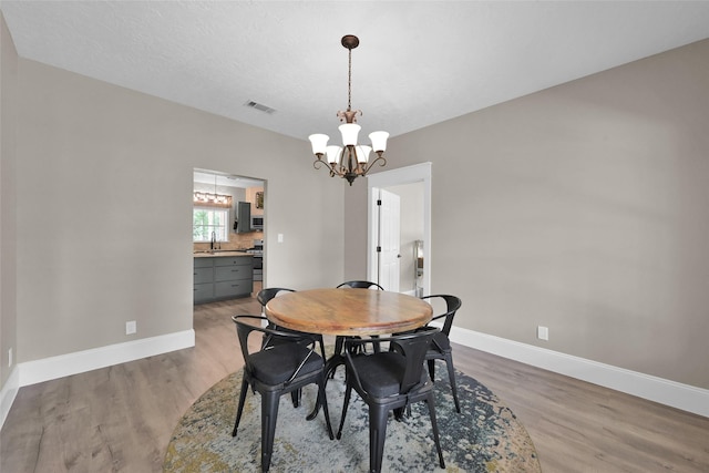 dining room featuring a chandelier, hardwood / wood-style floors, and sink