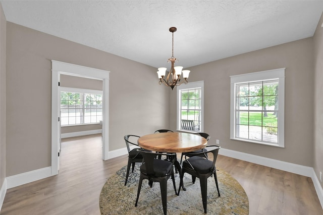 dining space with a chandelier, a textured ceiling, and light wood-type flooring