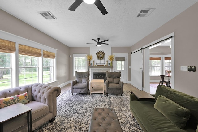 living room featuring hardwood / wood-style flooring, ceiling fan, a barn door, and a textured ceiling