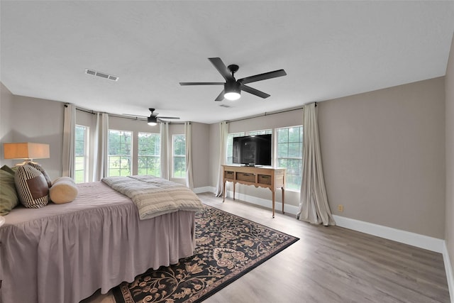 bedroom featuring hardwood / wood-style flooring, ceiling fan, and multiple windows