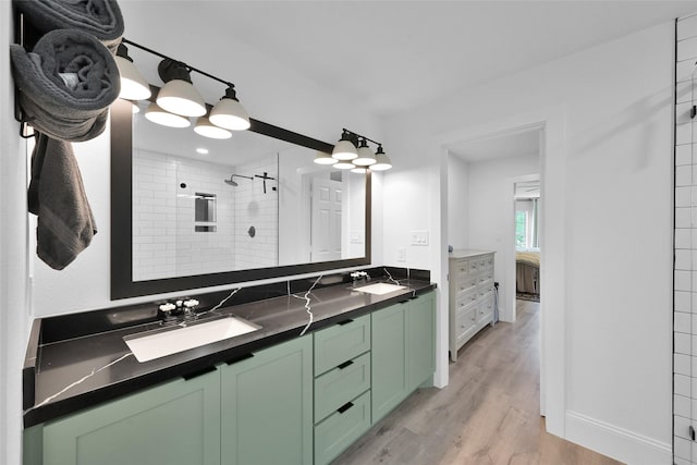 bathroom with tiled shower, vanity, and hardwood / wood-style flooring