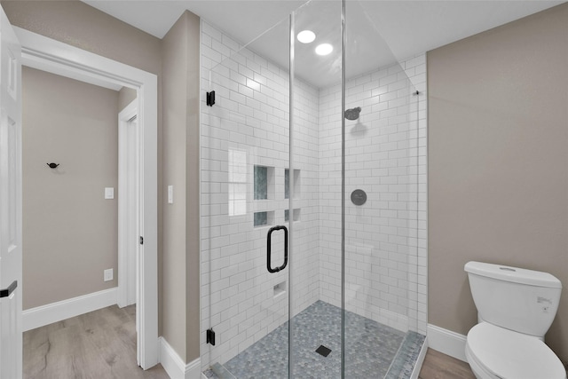 bathroom with hardwood / wood-style flooring, toilet, and a shower with shower door