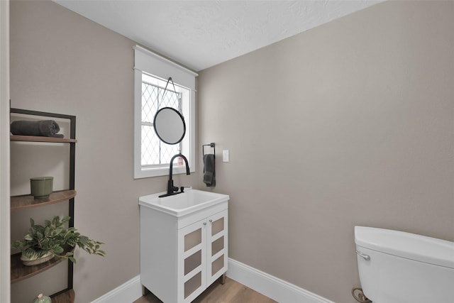 bathroom with hardwood / wood-style flooring, vanity, toilet, and a textured ceiling