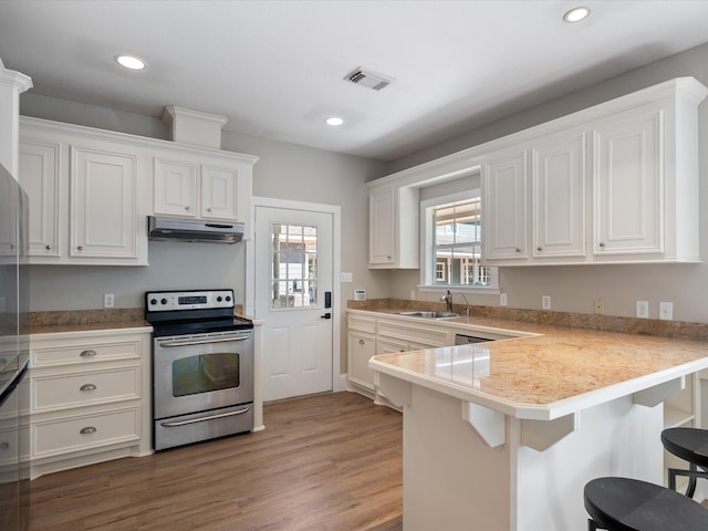 kitchen featuring kitchen peninsula, a kitchen breakfast bar, sink, white cabinets, and stainless steel electric range oven