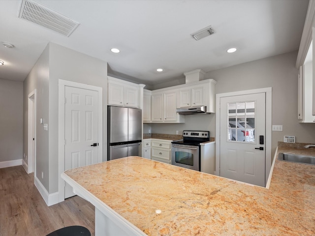 kitchen featuring kitchen peninsula, light wood-type flooring, stainless steel appliances, sink, and white cabinetry