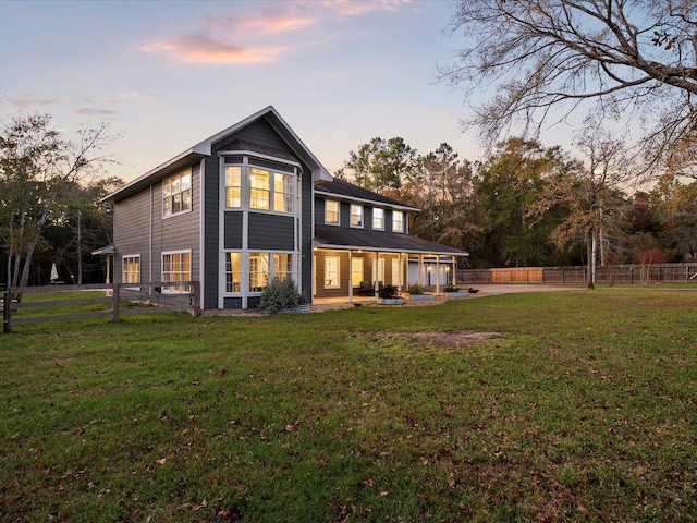 back house at dusk featuring a lawn