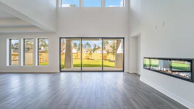 unfurnished living room with a high ceiling, plenty of natural light, and dark hardwood / wood-style floors