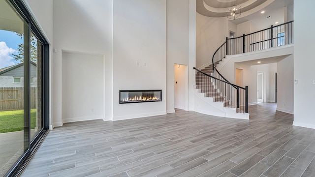 unfurnished living room with a high ceiling and light wood-type flooring