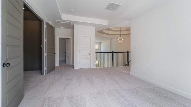 unfurnished bedroom with a notable chandelier, a tray ceiling, and carpet