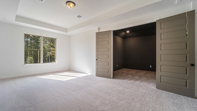 unfurnished bedroom with carpet and a tray ceiling