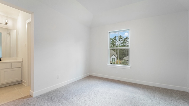 carpeted empty room featuring lofted ceiling and sink