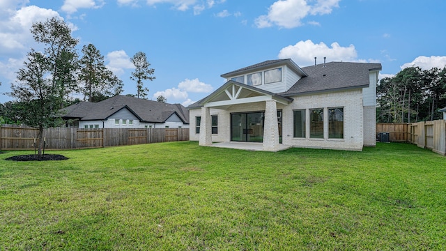 back of property with central air condition unit, a patio area, and a yard