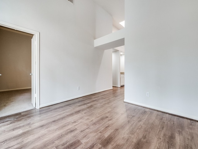 unfurnished living room featuring light hardwood / wood-style flooring and a high ceiling