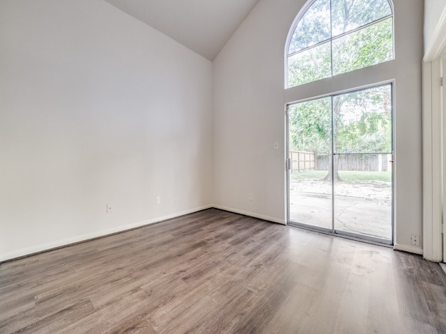 empty room featuring high vaulted ceiling and hardwood / wood-style floors