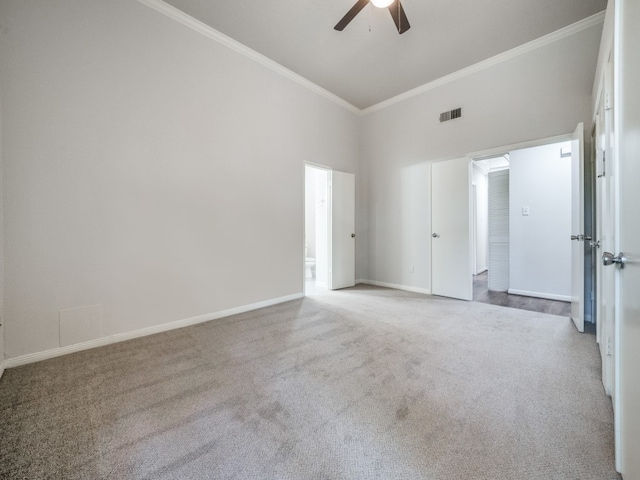 spare room featuring ornamental molding, ceiling fan, a high ceiling, and light colored carpet